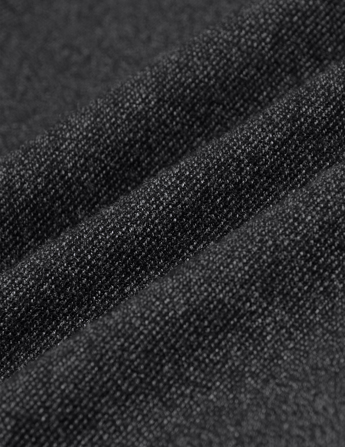 Nærbilde av Atelier Pants Relaxed i mørkegrått, i strukturert brutt twill med diskrete diagonale folder.